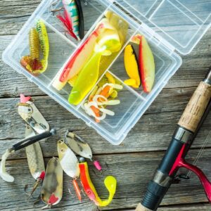 A box of fishing lures and a fishing rod.